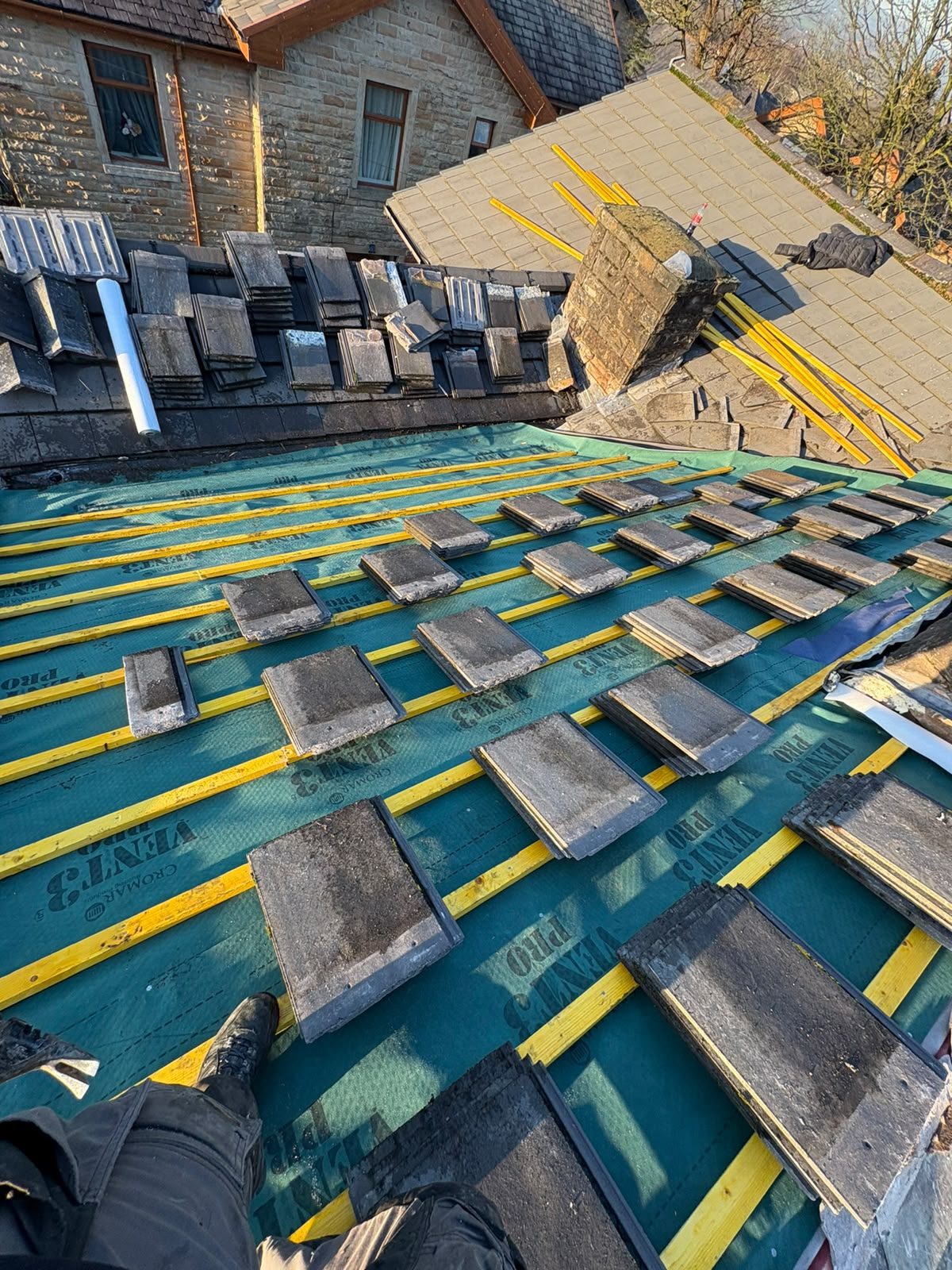 Breathable membrane and treated timber battens being laid during a roof strip and re-cover