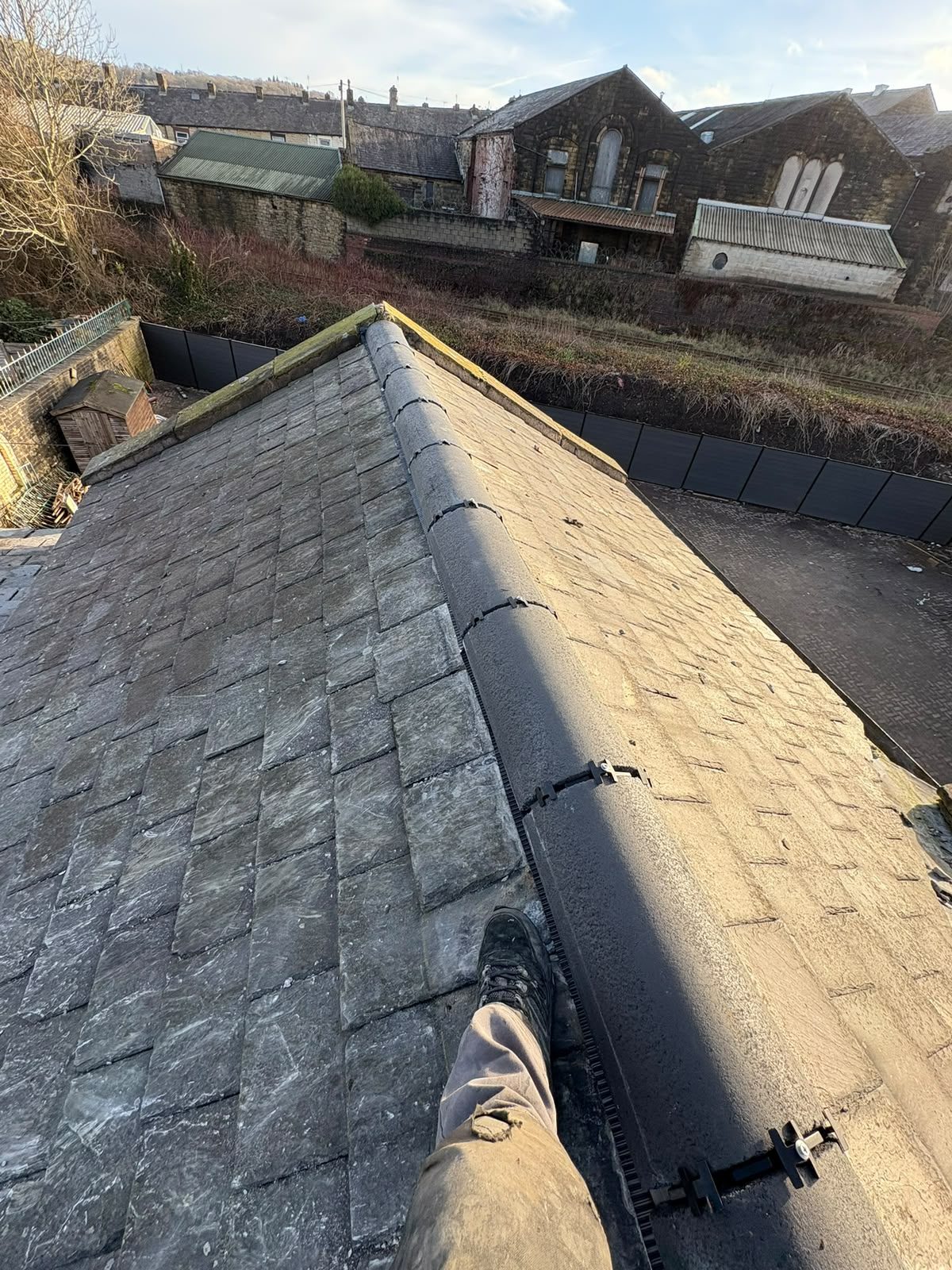Completed ridge repointing with dry ridge fixings along a stone slate roof