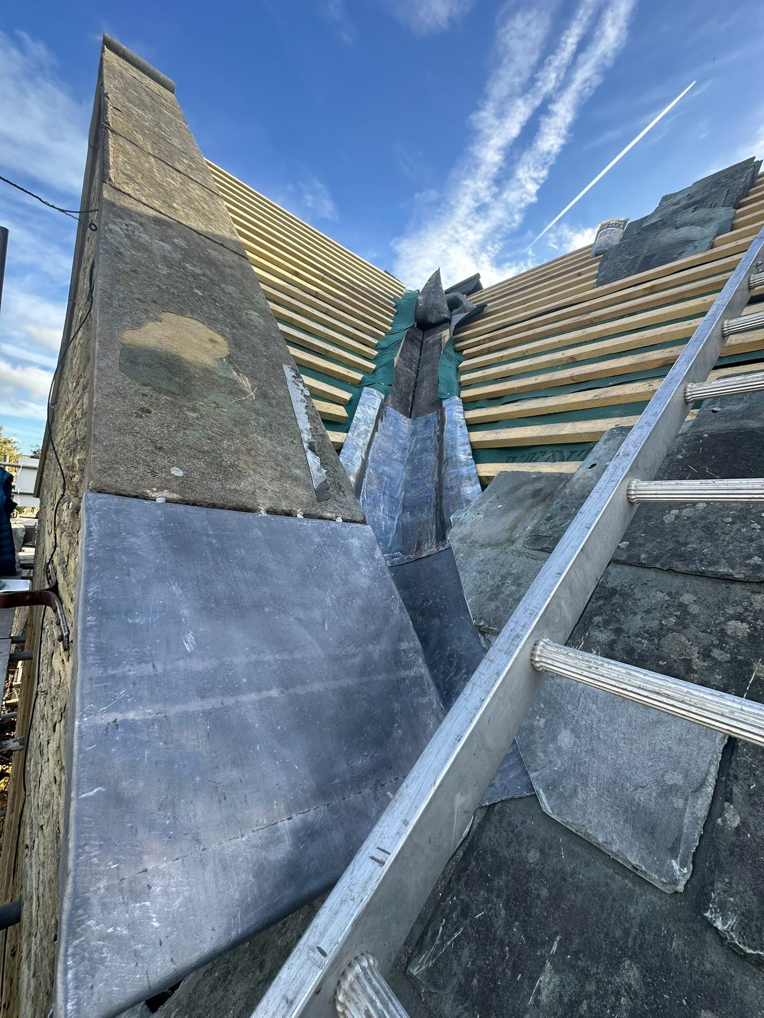 New lead valley dressed between two slate roof slopes on a stone property in Lancashire